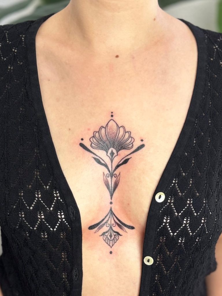 Symmetrisches florales Fineline Tattoo mit ornamentalem Motiv am Brustbein