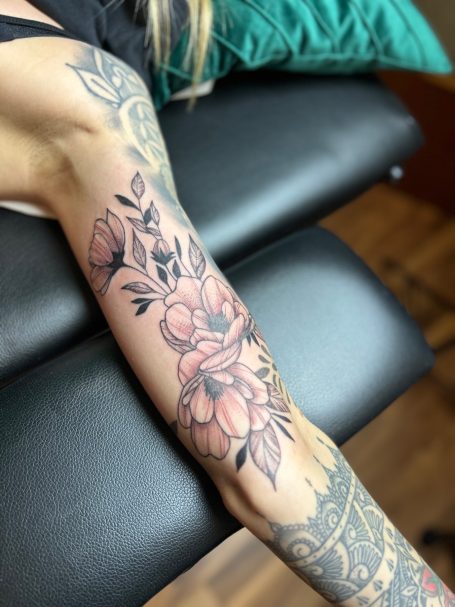 Florales Fineline Tattoo am Unterarm mit Blüten und Blättern