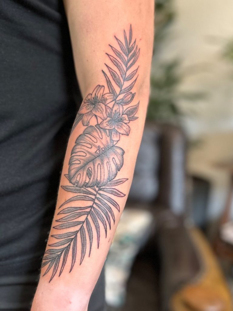 Botanisches Fineline Tattoo mit tropischen Blättern und feinen Linien am Unterarm