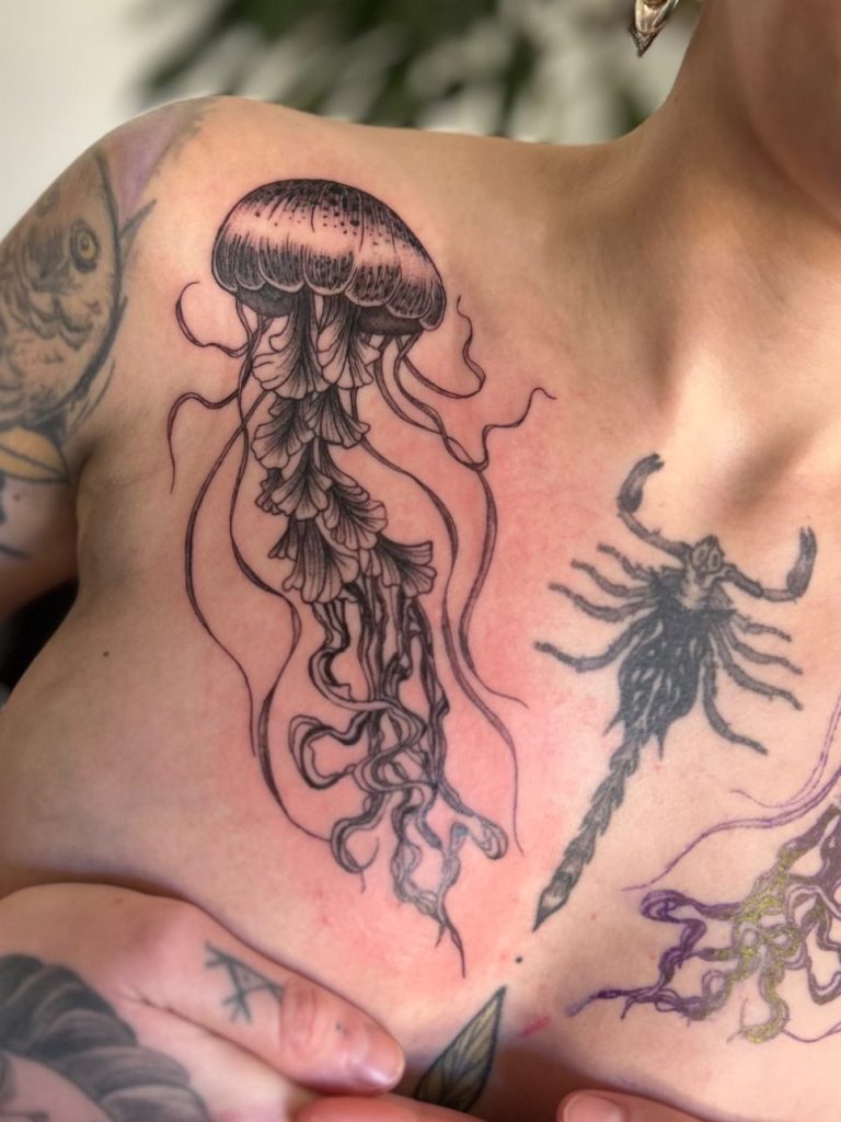 Detailreiches Black and Grey Quallen Tattoo mit feinen Linien und fließenden Tentakeln am Dekolleté