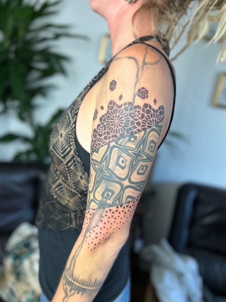 Geometrische Tattoo Erweiterung mit Mandala, Dotwork und ornamentalen Mustern am Oberarm