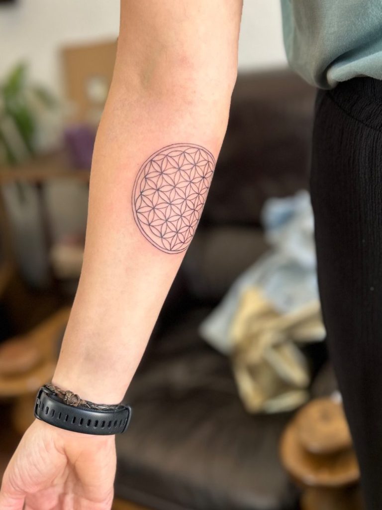 Geometrisches Fineline Tattoo mit Blume des Lebens am Unterarm