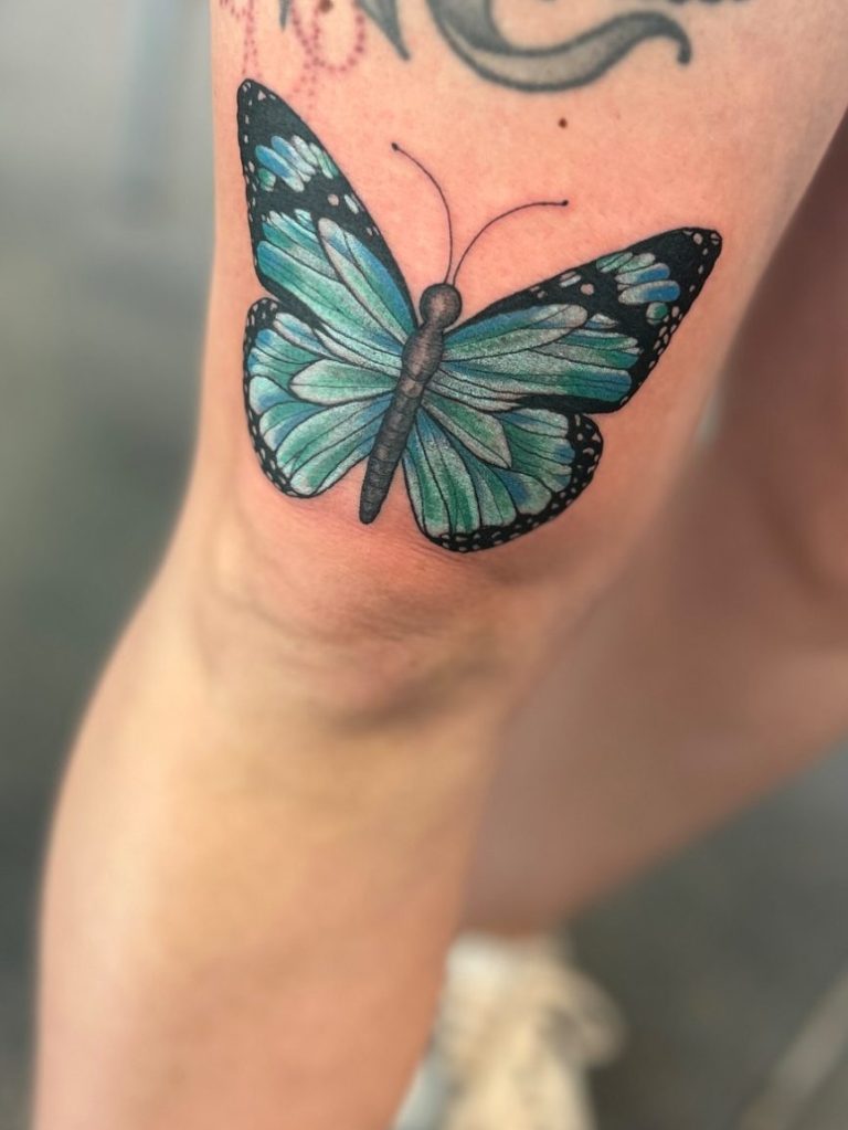 Farbiges Schmetterling Tattoo in Blau und Türkis am Oberschenkel