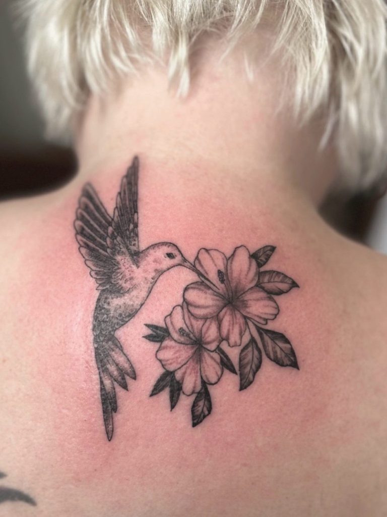 Kolibri Fineline Tattoo mit Blüten und feinen Black and Grey Schattierungen