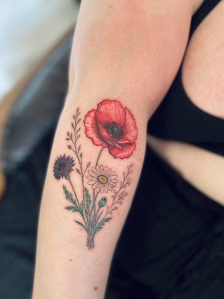 Florales Fineline Tattoo mit Mohnblume und Wildblumen in Farbe